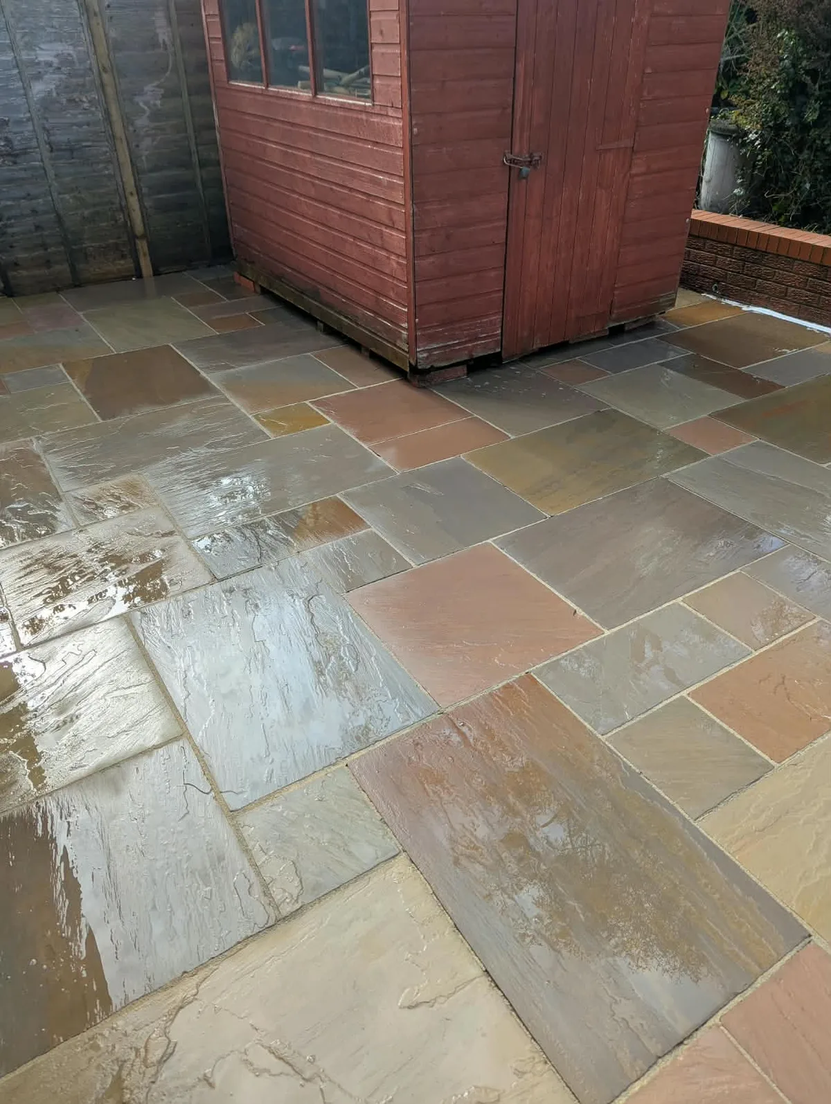 Clean paving beside the garden shed in Leek, still wet after cleaning.