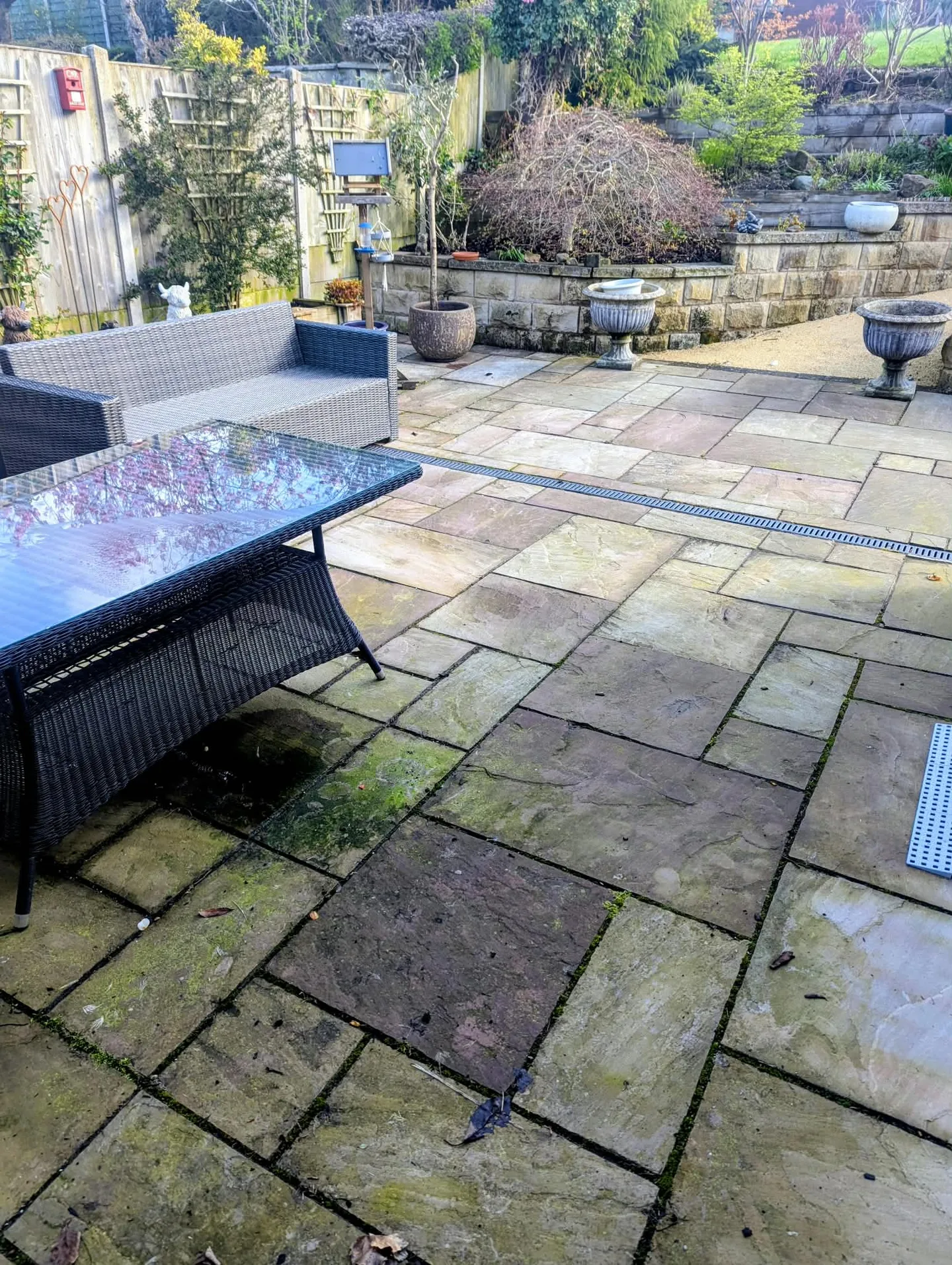 Garden patio in Uttoxeter before cleaning, with green staining around the outdoor seating.