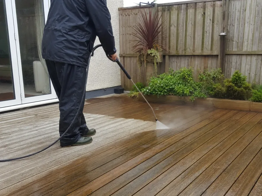 A worker carefully cleaning timber decking