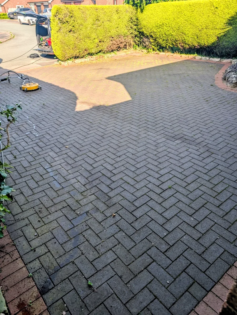 A large block-paved driveway before cleaning