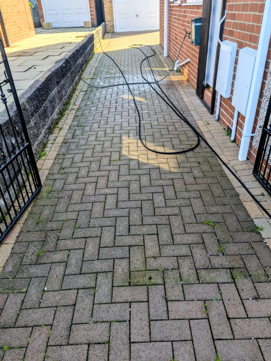A narrow block-paved side driveway before cleaning