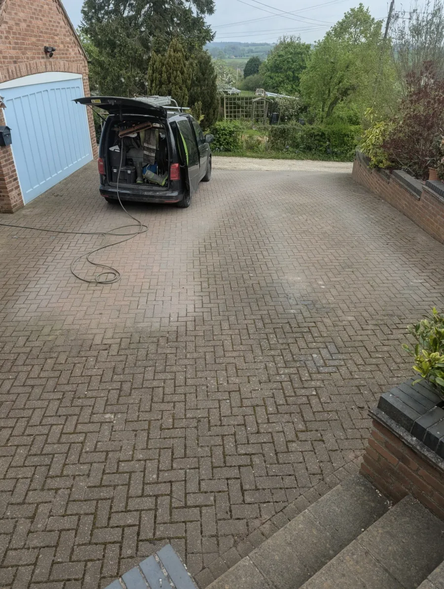 A block-paved driveway before cleaning, with the Tidy Jet Washing van on site