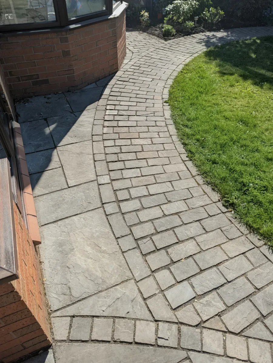 A curved paved garden path before cleaning