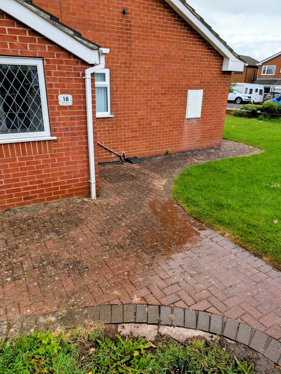 A block-paved path around a house before cleaning