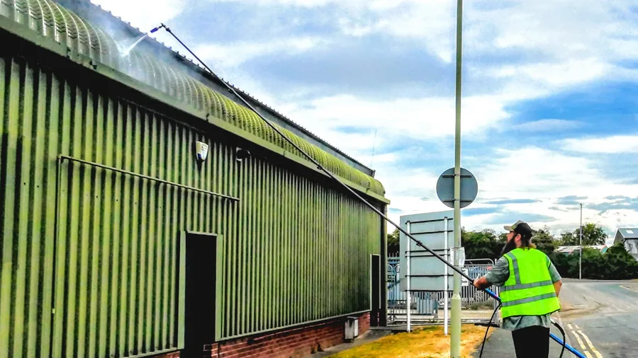 Mike cleaning the upper cladding of an industrial unit using a long-reach lance