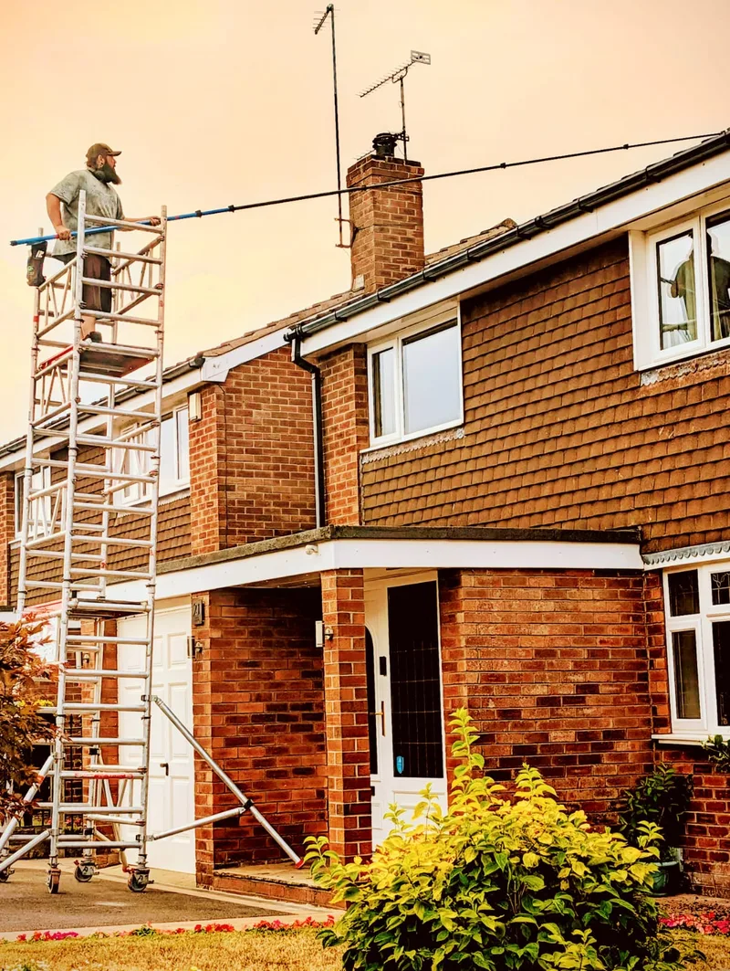 Roof cleaning from a mobile access tower at a residential property.