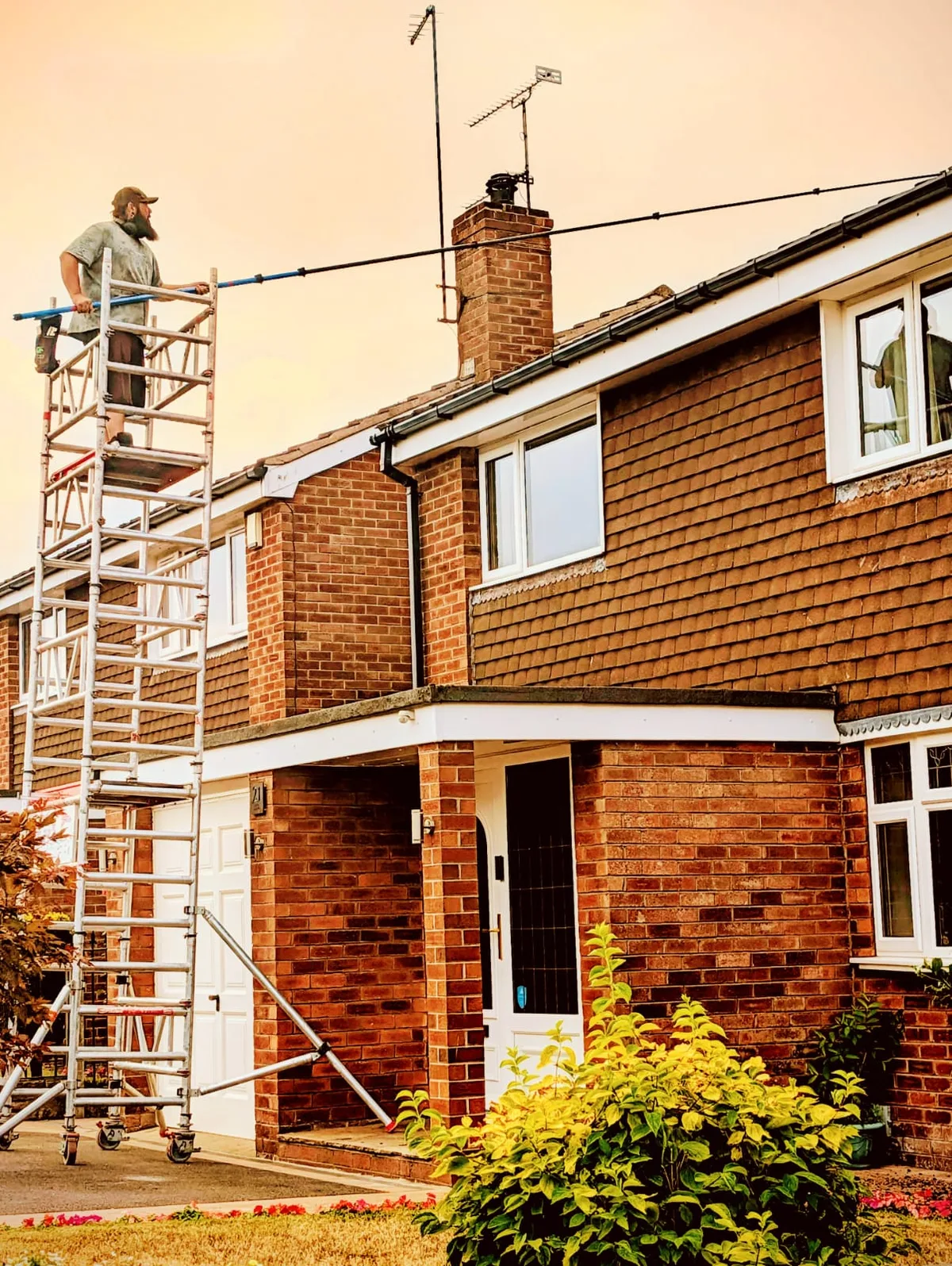 Roof cleaning from a mobile access tower at a residential property.