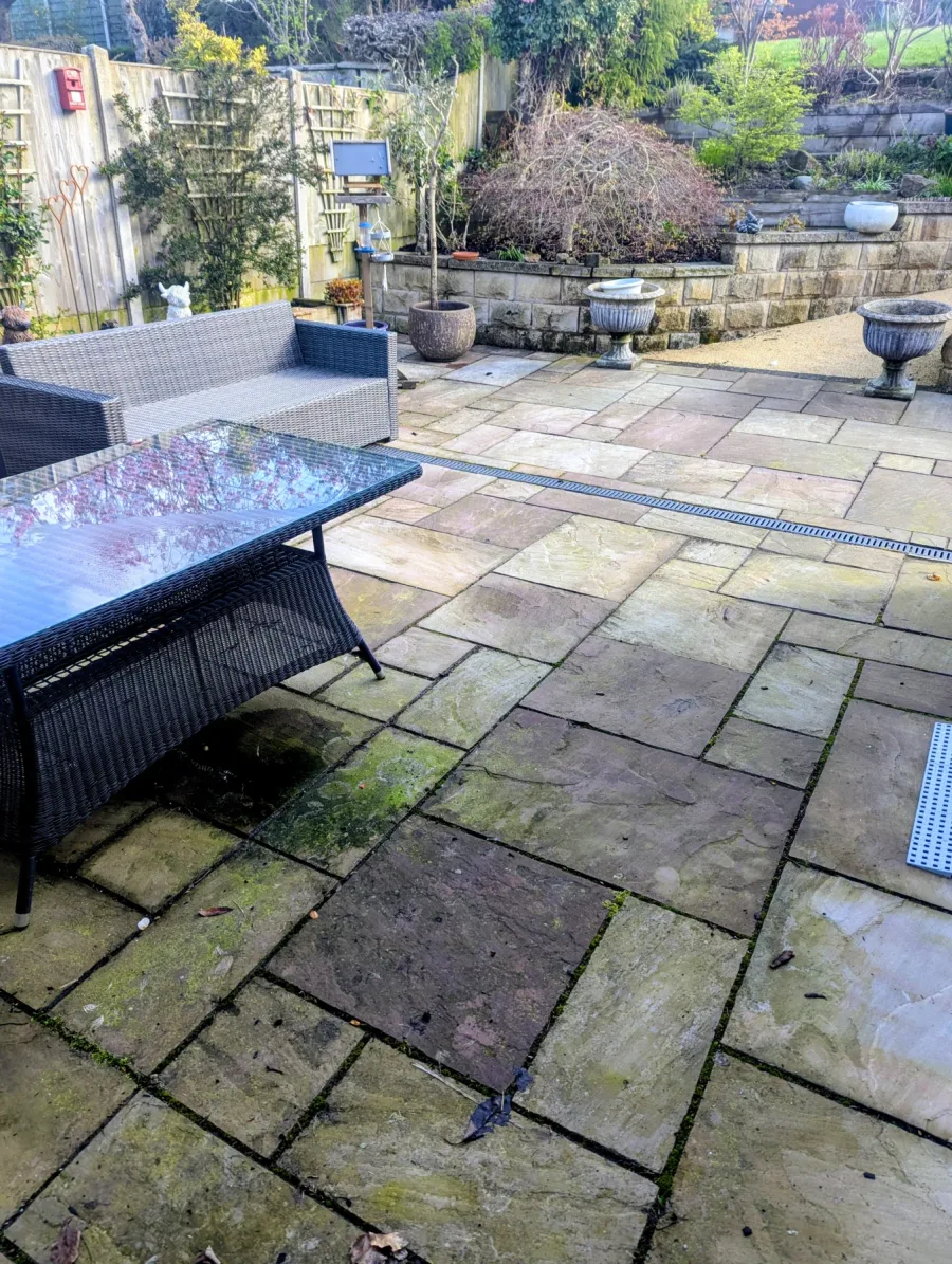 A garden patio with algae and weather staining before cleaning