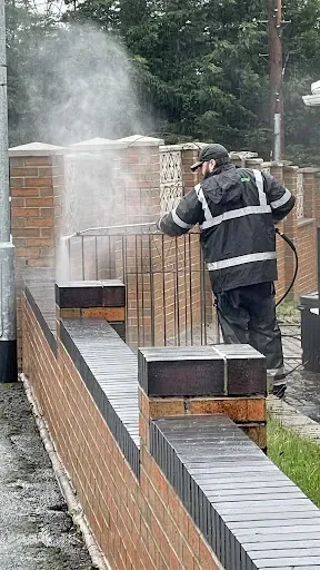 Mike using pressure-washing equipment to clean exterior brick walls.
