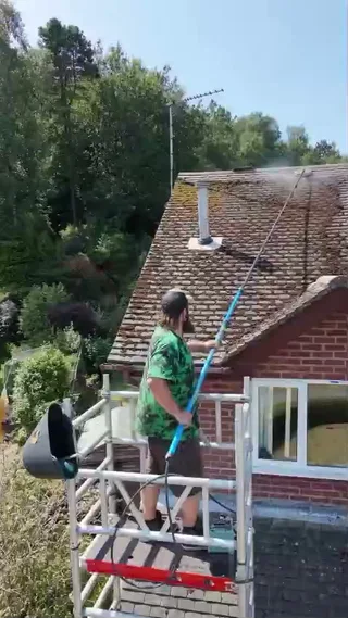 Mike working from a mobile access tower beside the roof of a residential property.