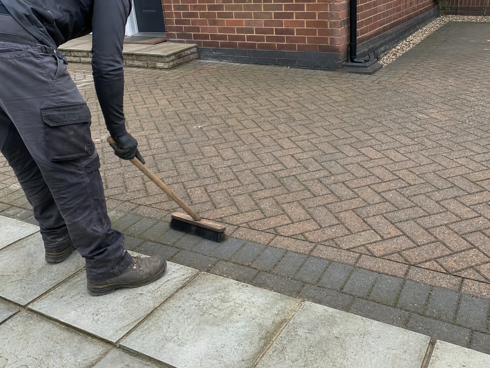 Representative image of a cleaned block-paved driveway being carefully finished by hand.